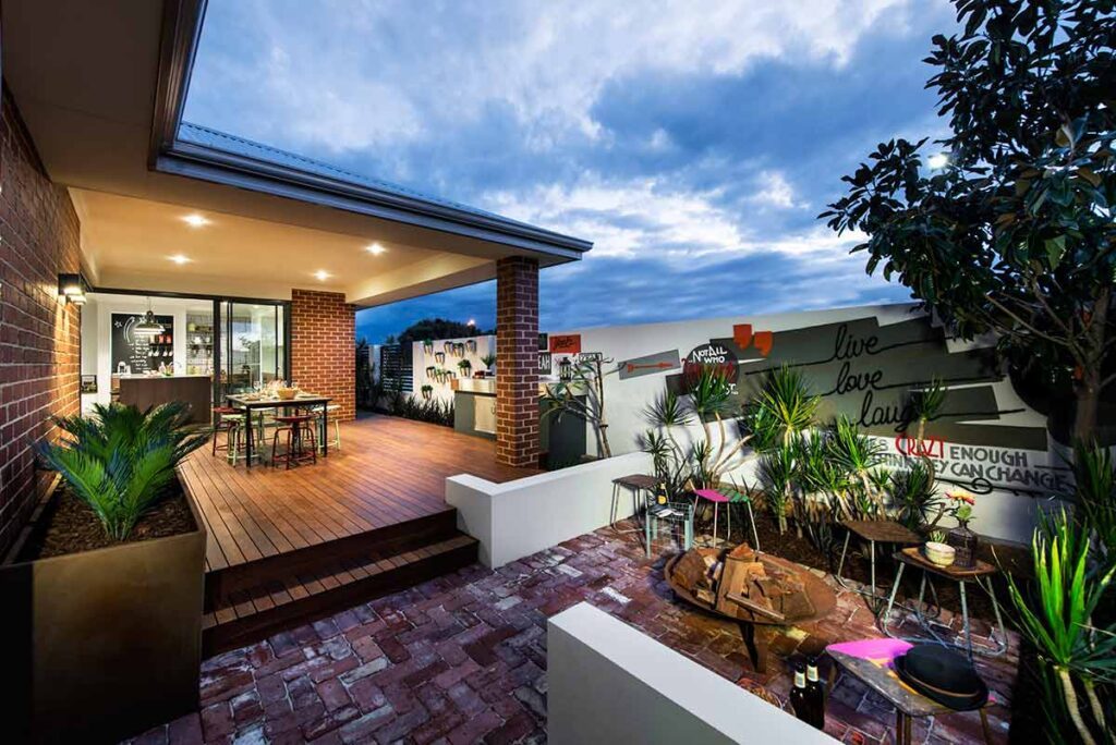 Timber deck and brick courtyard with a planted retaining wall at dusk