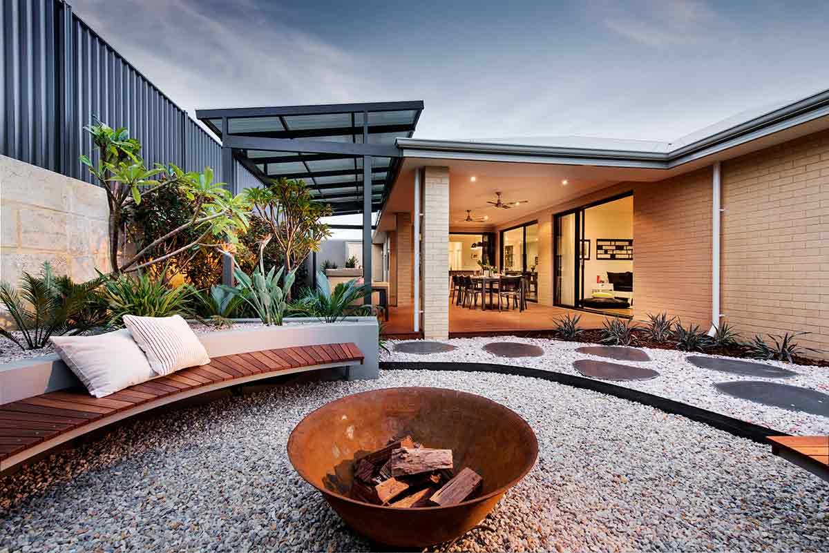 Completed Perth courtyard at dusk with a timber bench seat, fire bowl and planting